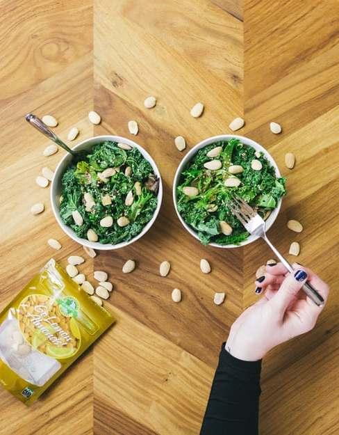 Dwie miseczki ze szpinakiem ułożona na drewnianym blacie