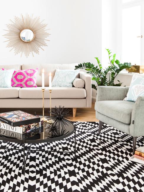 wzory geometryczne Salon z jasną kanapą, fotelem, czarnym stolikiem kawowym oraz dywanem we wzory geometryczne