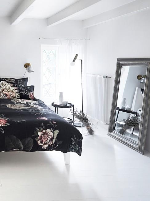 Fragment sypialni z łożkiem, stolikiem nocnym, lampą oraz suszoną lawendą w wazonie