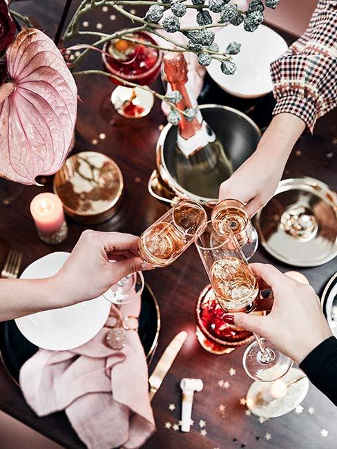 osoby w geście toastu z kieliszkami szampana nad stołem