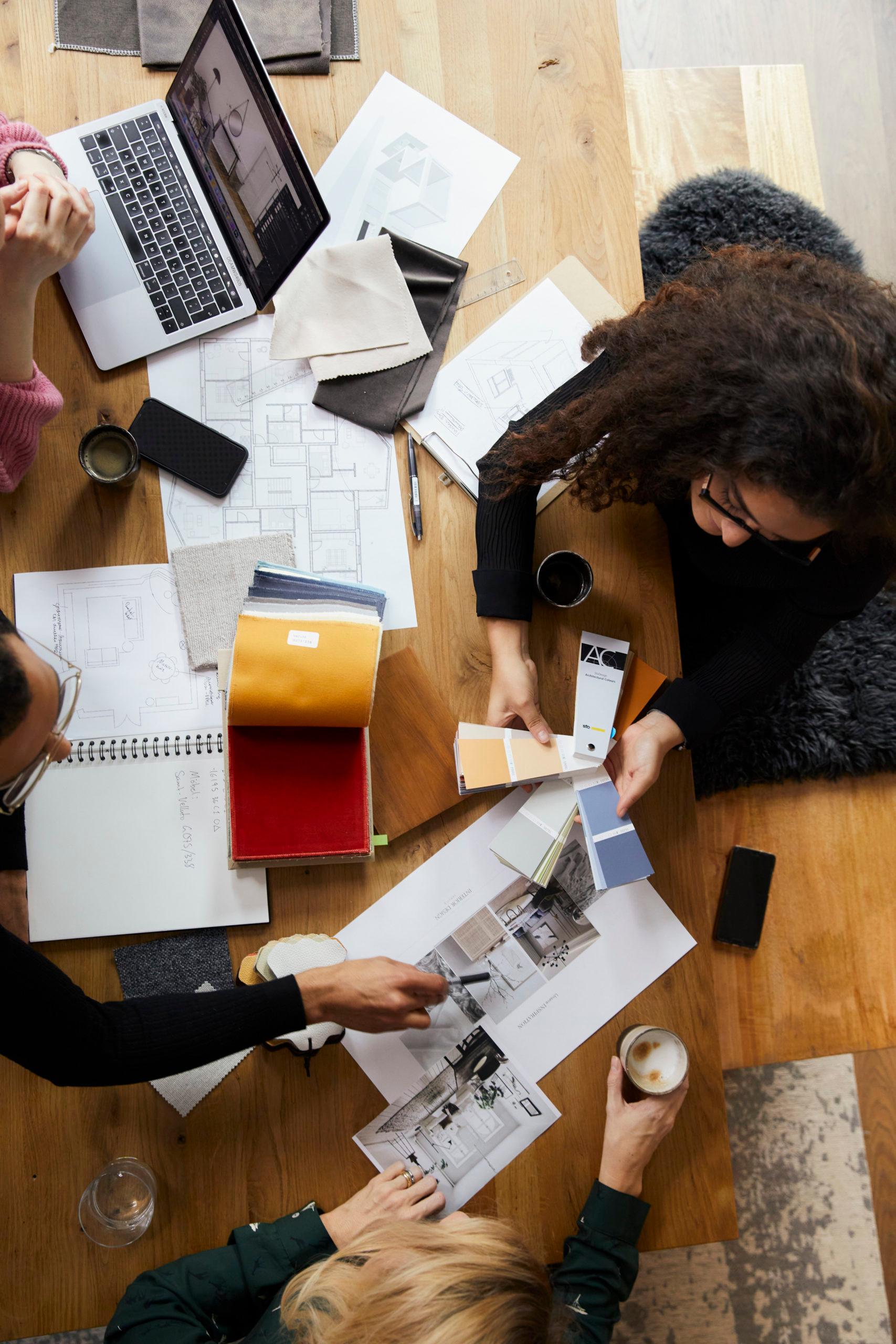 Trzy osoby siedzące przy stole w biurze i pracujące