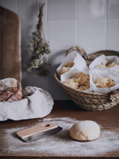 Fragment kuchni w stylu rustykalnym z drewnianym blatem oraz białą ścianą z artykułami kuchennymi