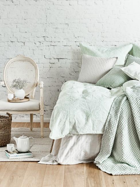 Łóżko zaścielone poduszkami i pledami w kolorze jasnej zieleni