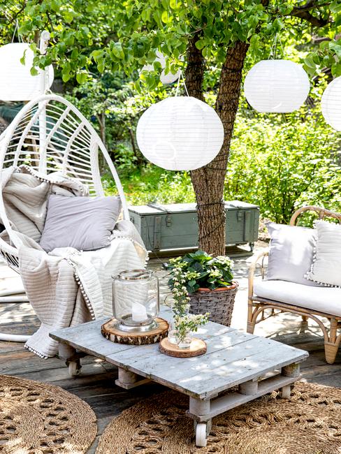 Zaaranżowany ogród z wiszącym fotelem, stolikiem z plety oraz sofą