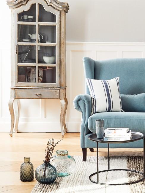 Jasny salon w stylu country z niebieską kanapą oraz drewnianym kredensem