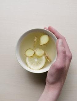 Biały kubek z naparem z cytryny i imbiru