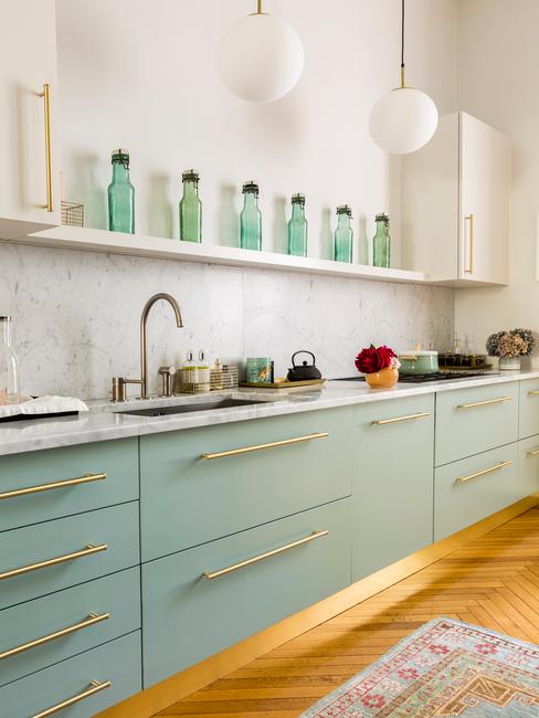 Fragment salonu z aneksem kuchennym z meblami o lekko turkusowym kolorze