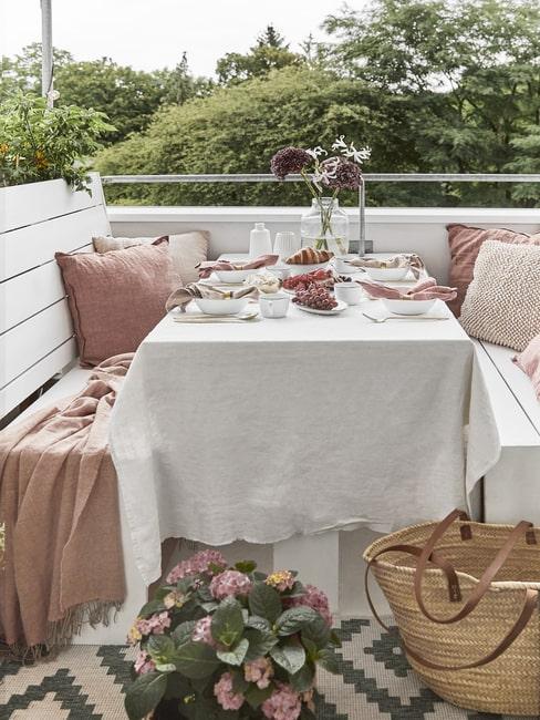 Balkon z dwoma ławkami oraz nakrytym stołem