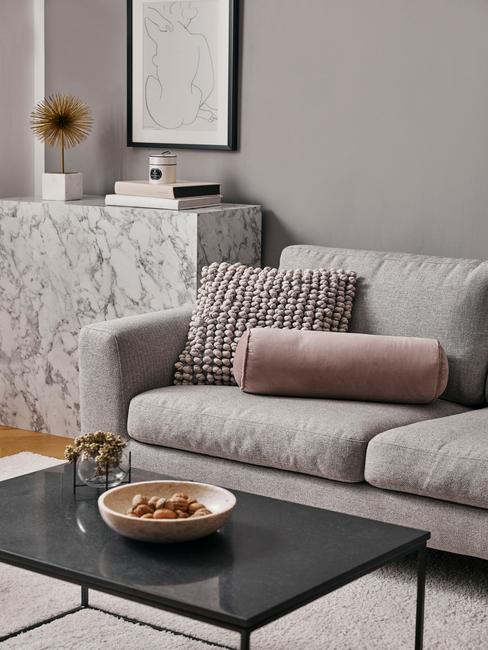 Salonw stylu glam z szarą kanapą, marmurową komodą oraz dekoracjami w kolorze brudnego różu