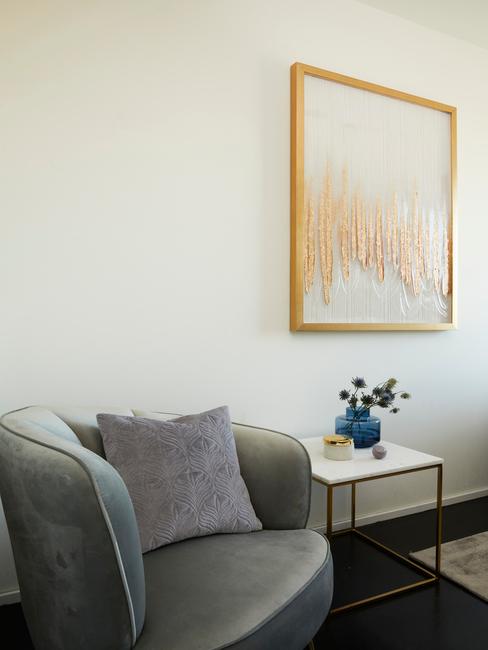 Beżowy salon z szarym krzesłem, bialtym stolikiem oraz wazonem z kwiatami