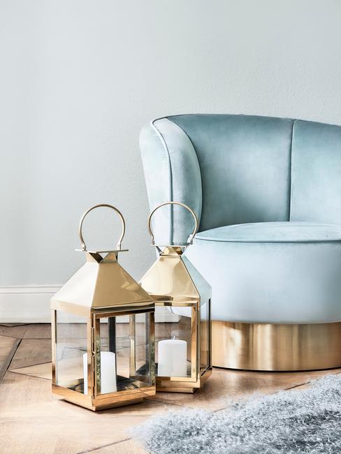 Turkusowy fotel oraz złote latarenki w salonie