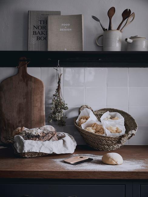 Biała kuchnia wyłożona kafelkami z czarną półką z książkami kucharskimi