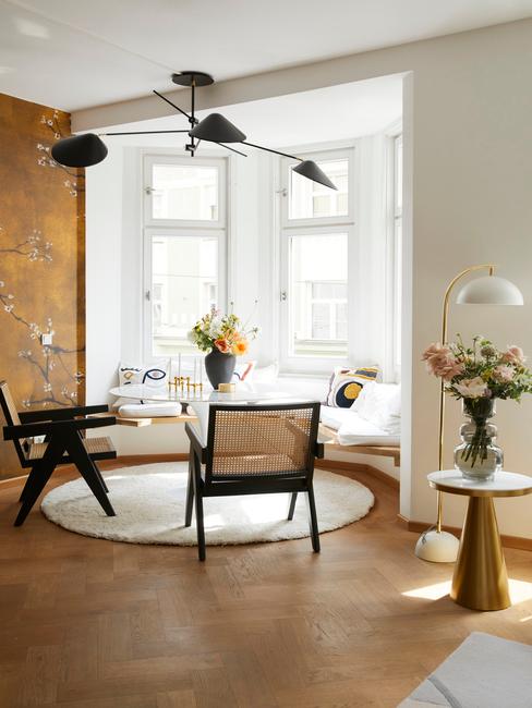 Kącik jadalny ustawiony salonie ze złotą ściną oraz dekoracjami