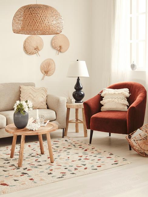 Salon boho z beżową sofą, pomarańczowym sotelem, drewnianym stolikiem i dywanem z motywm terazzo