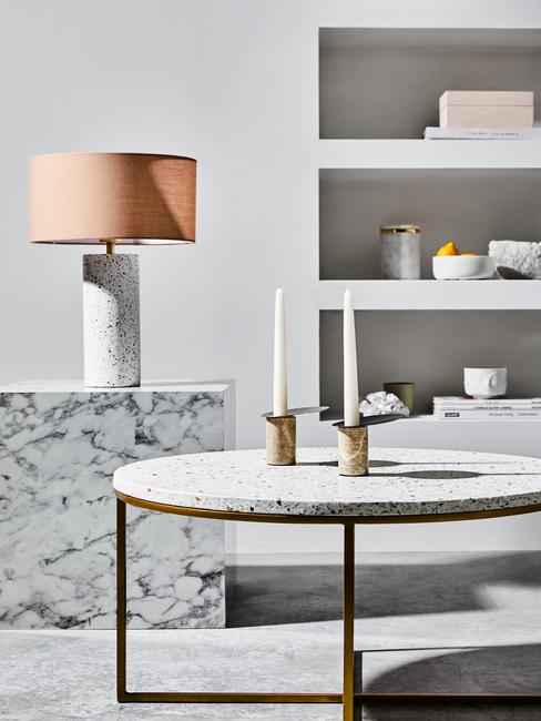 Białe pomieszczenie z półką, marmurowym stolikiem z lampą oraz sotlikiem z lastriko