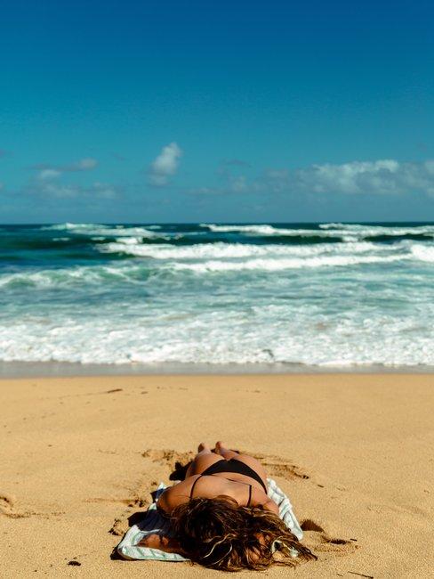 Jak utrzymać opaleniznę Kobieta opalająca się na plaży