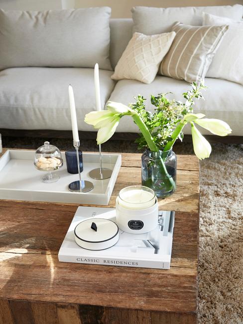 taca deckoracyjna z marmuru ze świecznikiem na drewnianym stoliku kawowym obok wazonu z białymi daliami