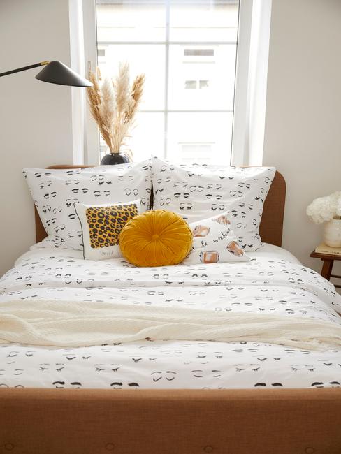 Mała sypialnia w bloku z kolorową pościelą oraz dekoracją z trawy pampasową