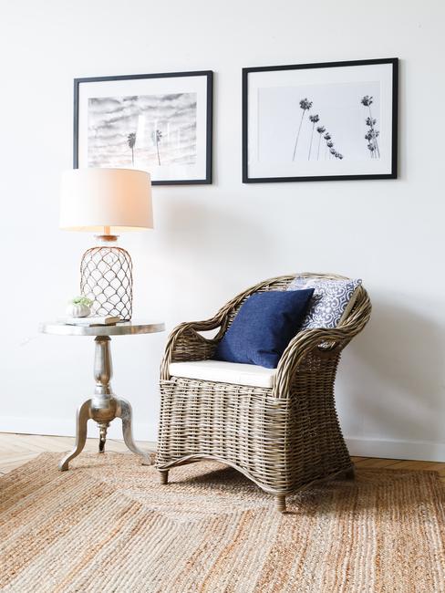 Białe wnętrze z obrazkami, wiklinowym krzesłem oraz stolikiem z lampką