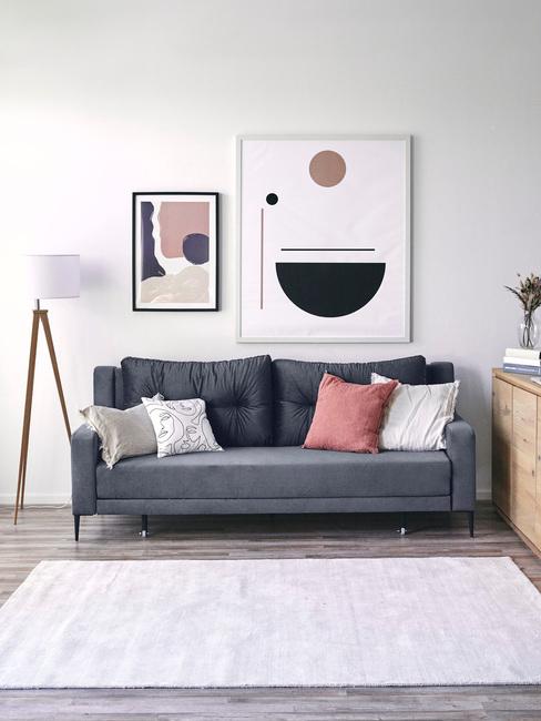 Wnętrze salonu w stylu skandynawskim z ciemnoniebieską sofą, poduszkami oraz obrazem