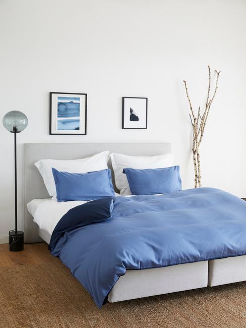 sypialnia w łożkiem, lampą oraz dekoracją z gałęzi