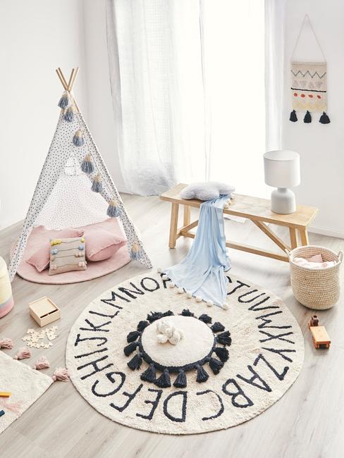 Kącik zabaw w białym pokoju z namiotem tipi, poduszkami i zabawkami