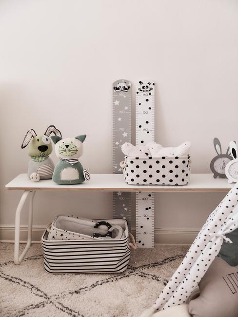 Fragment pokoju dziecięcego z białym stolikiem, zabawkami, miarkami wzrostu i fragmentem namiotu