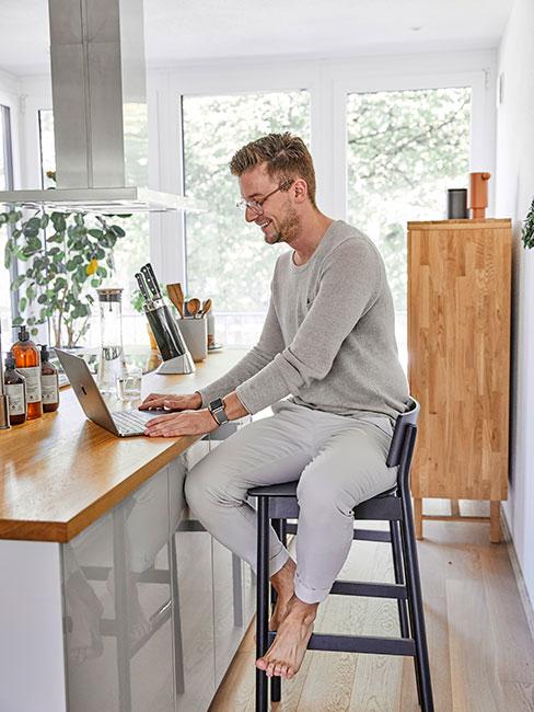 Męóczyzna pracujący na laptopie w kuchni