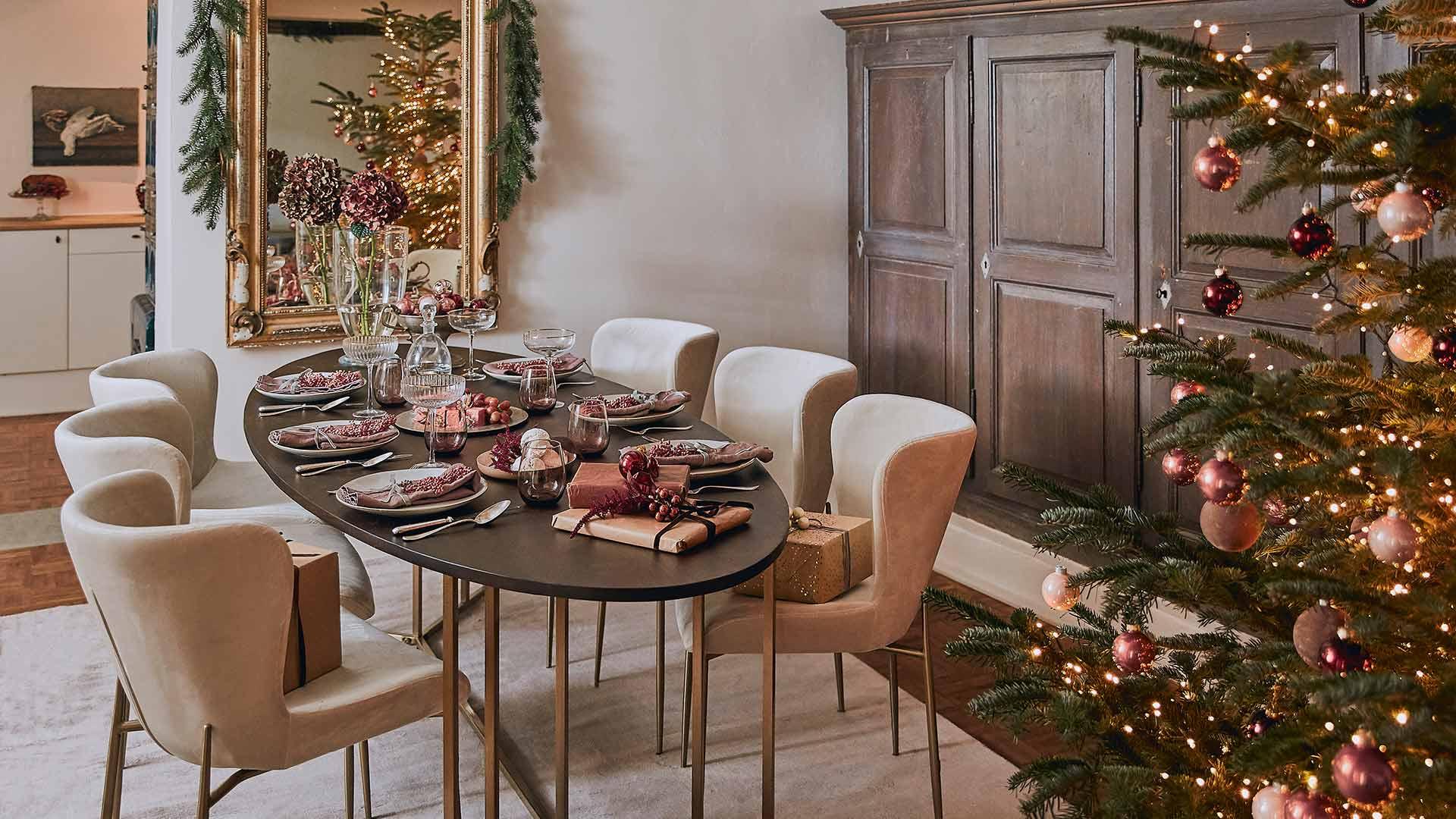 Wnętrze jadalni z drewnianym stołem, beżowymi krzesłami oraz choinką