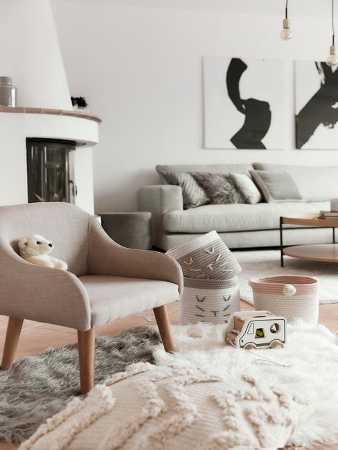 Rodzinny salon skandynawski w bieli, z szarą sofą, beżowym krzesłem, dywanem oraz kominkiem