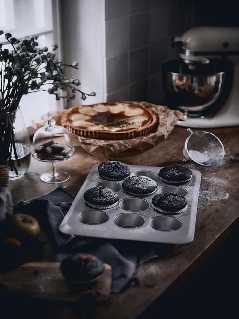 Czekoladowe babeczki w blaszcze na muffiny na drewnianym blacie w kuchni