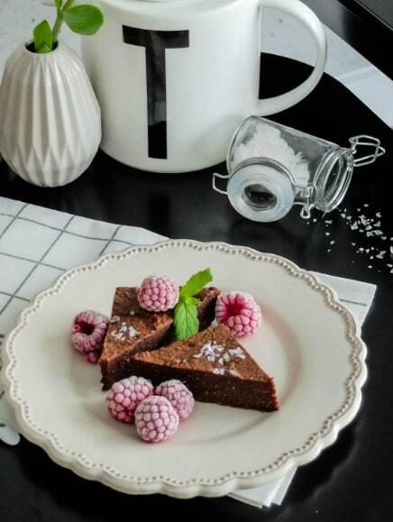 Bezglutenowe brownie z fior de sal na białym, deserowym talerzu na ściereczce w kratę