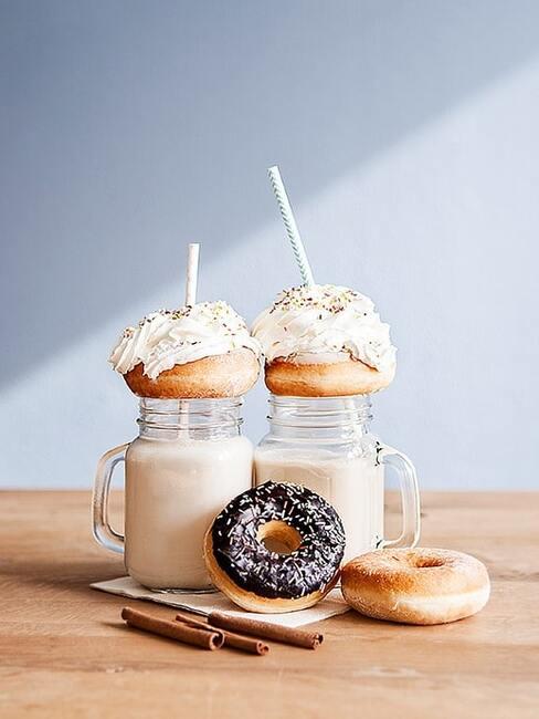 chai latte Dwie szklanki z uchem z chai latte oraz donuty na drewnianym blacie