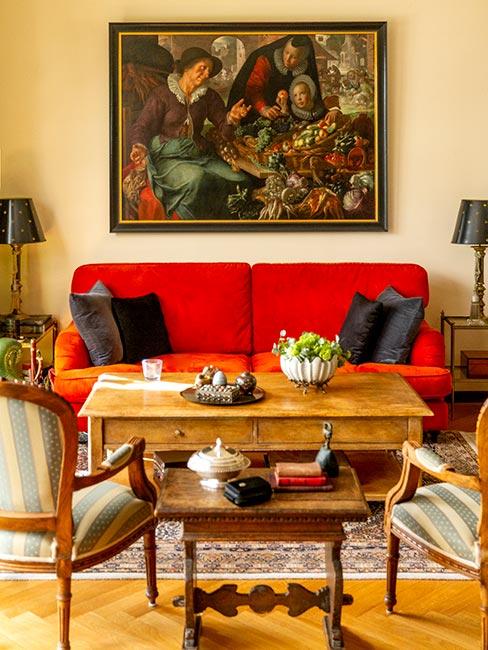 salon w stylu pałacowym z czerwoną sofą, rustykalnym stolikiem kawowym z drewna i obrazem na ścianie