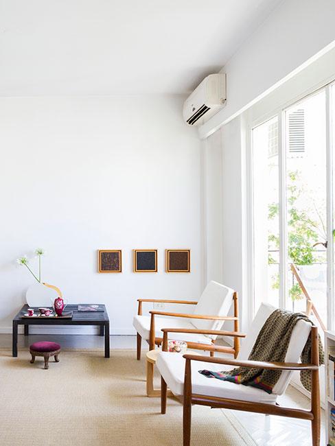 Jasny minimalistyczna salon z beżowymi fotelami z drewnianymi oparciami i niską komodą