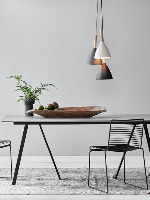 Minimalistyczny czarny stół do jadalni z trzema lampami wiszącymi o różnej długości