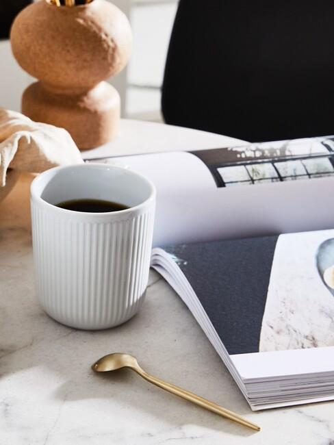 Biała, ceramiczna filiżanka z espresso obok magazynu wnętrzarskiego