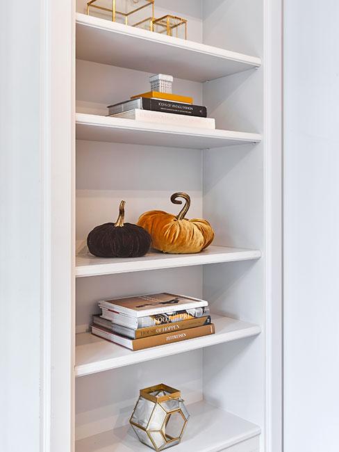 Biały regał udeokorowany książkami, dyniami z aksamitu i świecznikami
