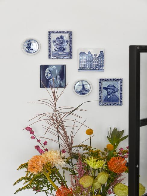 porcelanowe obrazki z białoniebieskiej porcelany z delft na ścianie za kolorowym bukietem polnych kwiatów