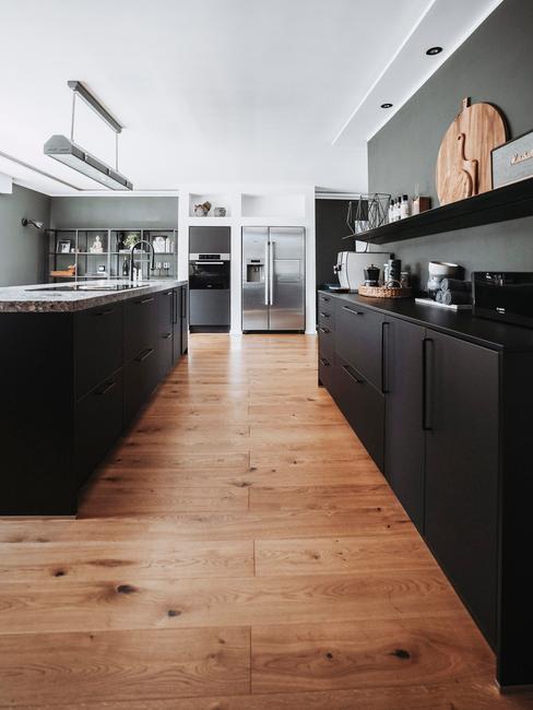 Industrialna kuchnia z ciemną ścianą, czarnymi frontami szafek, drewnianym parkietem oraz dodatkami
