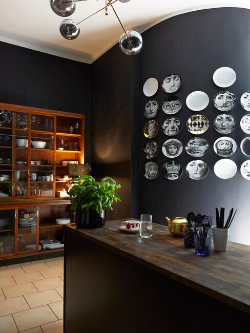 Kuchnia z czarną ścianą, na której znajdują się talerze, drewniana półka oraz wyspa kuchenna