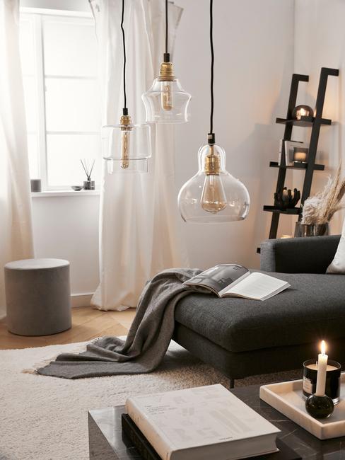 Nastrojowo oświetlony salon, czarna kanapa i szare ściany