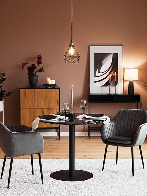 Stół do jadalni z krzesłami z szarego aksamitu na tle ściany w ciepłym pudrowym różu