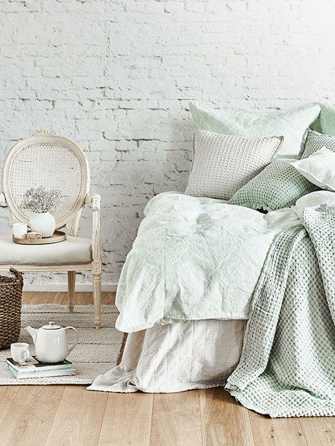 Sypialnia z zielonkawą pościelą i bieloną ścianą z cegły