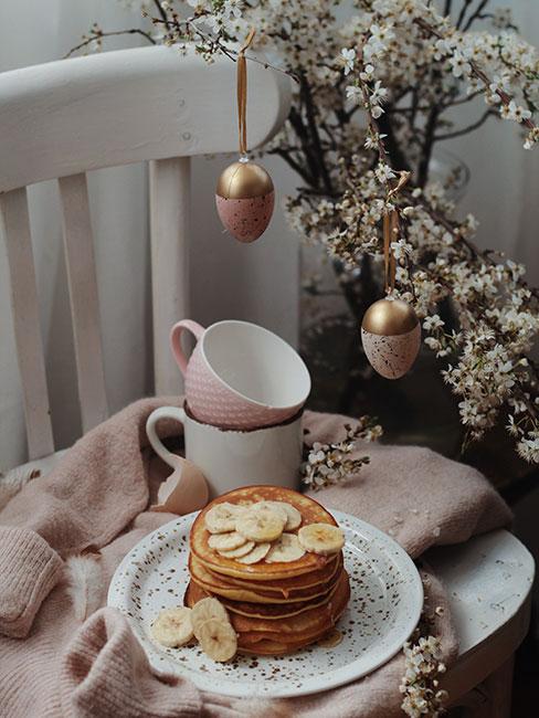 Romantyczna różowa aranżacja wielkanocna na białym krześle pod gałązkami jabłoni