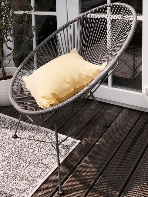 Zbliżenie na ażurowe krzesła na balkonie z żółtą poduszką