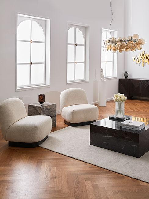Salon z dwoma nowoczesnymi fotelami boucle, czarnym stolikkiem z marmuru