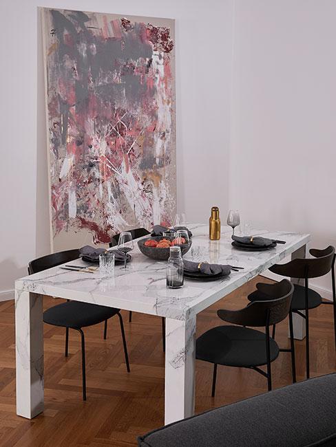 Jadalnia z dużym stołem z białego marmuru, czarnymi krzesłami z aksamitu i dużym abstrakcyjnym obrazem