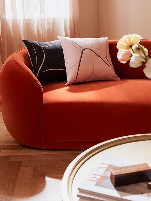 Pomarańczowa obła sofa z poduszkami z motywami kobiet
