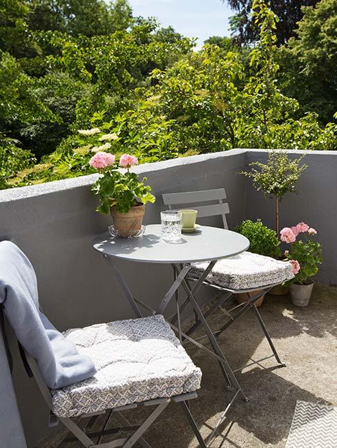 maly szary balkon z metalowymi meblami